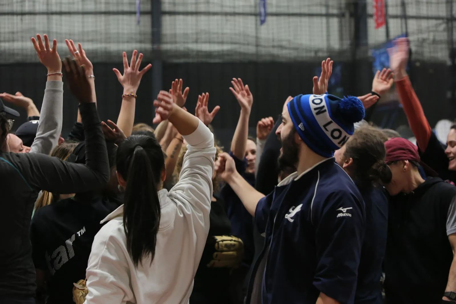 London Mets players with their hands raised in an end-of-session huddle at an indoor training night